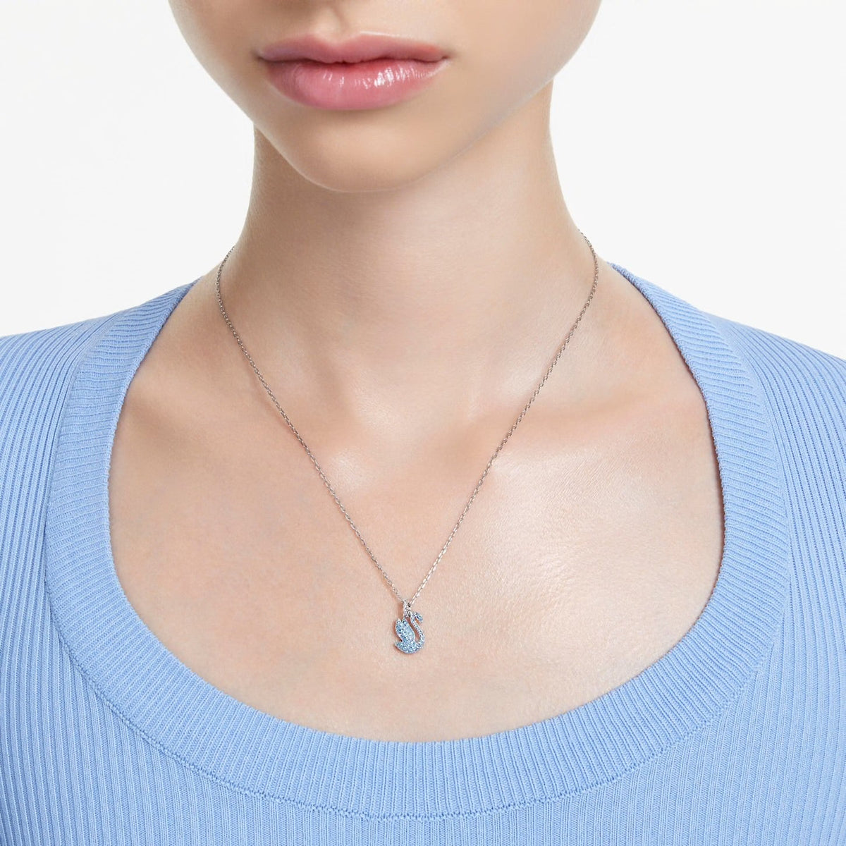 Model wearing Swarovski baby blue swan necklace with light blue top